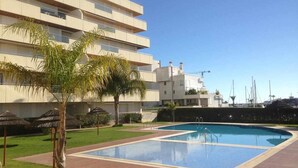 Un hotel moderno con piscina, palmeras y un cielo azul despejado.