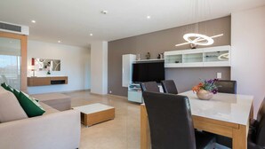 Una sala de estar moderna con un sofá, una mesa de centro, un televisor y un comedor con una mesa y sillas.
