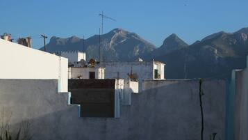 A residential area with white buildings, a staircase, and a mountain range in the background.
