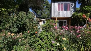 Ein Holzhaus, umgeben von üppigem Grün und bunten Blumen.