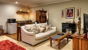 Ein Wohnzimmer mit einer Couch, einem Couchtisch und einem Kamin. Es gibt eine Küchenzeile mit Kühlschrank und Mikrowelle.
