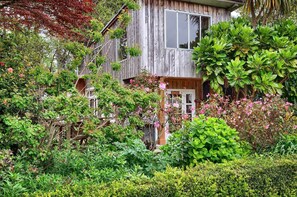 A rustic wooden house surrounded by lush greenery and flowering plants. - Quiet, relaxing cottage in a rural setting (Levin)