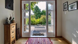 Ein Zimmer mit Holzboden, einem Schrank mit Schubladen, einem Teppich und einer Tür zu einem Garten mit einem Weg.