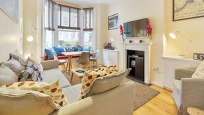 A living room with a fireplace, a dining area, and a sofa set. - Stylish self contained patio Garden Apartment in London’s fashionable SW6 (Fulham)