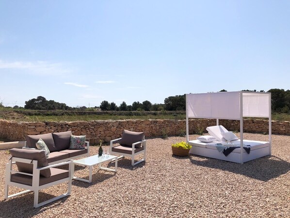 An outdoor seating area with a white canopy bed, two sofas, and a table.