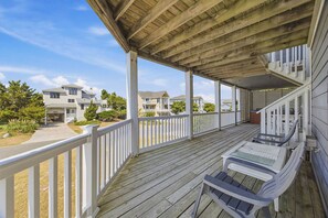 A wooden deck with a covered area, white railings, and a view of residential buildings.