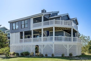 A two-story house with a balcony, a covered porch, and a lattice fence.