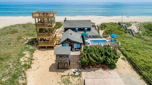 A beachfront property with a wooden deck, a pool, and a beach view. - The Beach House | Oceanfront | Dog Friendly, Private Pool, Hot Tub | Nags Head (Nags Head)