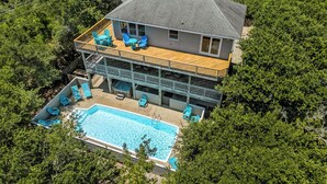 A two-story house with a swimming pool, multiple decks, and outdoor seating.