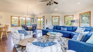 A spacious living room with a blue sofa set, a marble-patterned sofa, and a dining area with wooden chairs.