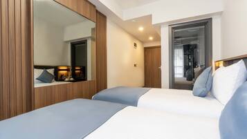 Una habitación de hotel moderna con dos camas, un espejo grande y un armario.