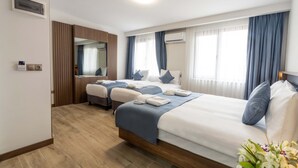 Habitació d'hotel amb dos llits, un sòl de fusta, un mirall gran i un aparell d'aire condicionat.