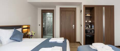 A hotel room with two beds, a wardrobe, and a bathroom visible through an open door.