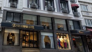 Un hotel de diverses plantes amb balcons, una botiga emblemàtica a nivell del carrer i una entrada ben visible.