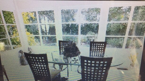 Eine Terrasse mit einem Glastisch und zwei Stühlen.