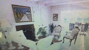 Ein Zimmer mit einem Bett, einem Schminktisch, einem Sessel, einem kleinen Tisch und einem Bild an der Wand.