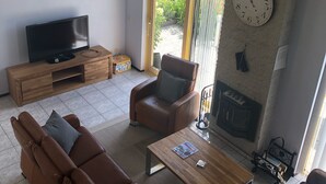A living room with a sofa, armchairs, a coffee table, a TV, and a fireplace.