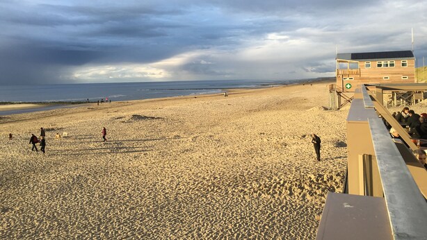 A beach with a lifeguard tower and a wooden building.