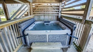 A hot tub with stone walls and wooden railings, surrounded by a wooden deck. - Splash and Go | 1135 ft from the beach | Private Pool, Hot Tub | Nags Head (Nags Head)