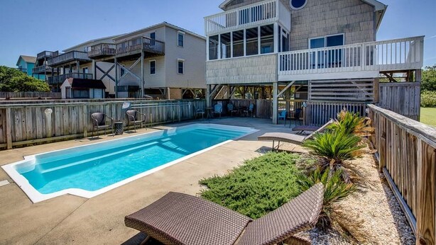 A two-story house with a swimming pool, outdoor seating, and a wooden deck. - Splash and Go | 1135 ft from the beach | Private Pool, Hot Tub | Nags Head (Nags Head)