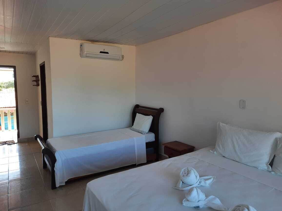 A hotel room with two single beds, a wooden headboard, a small bedside table, and an air conditioning unit on the wall.