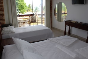 Habitación de hotel con dos camas, un escritorio, una silla, televisión y vista al exterior.