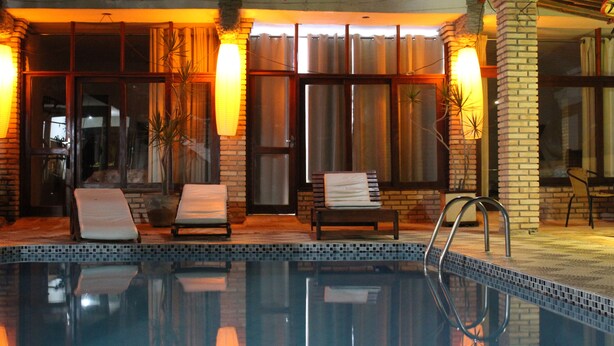 Una piscina con sillones de descanso y un muro de ladrillo.
