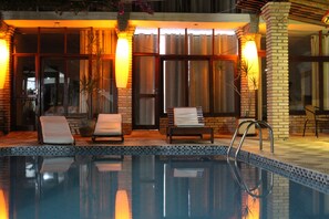 A swimming pool with lounge chairs and a brick wall. - Pousada Água de Fuego (Maragogi)