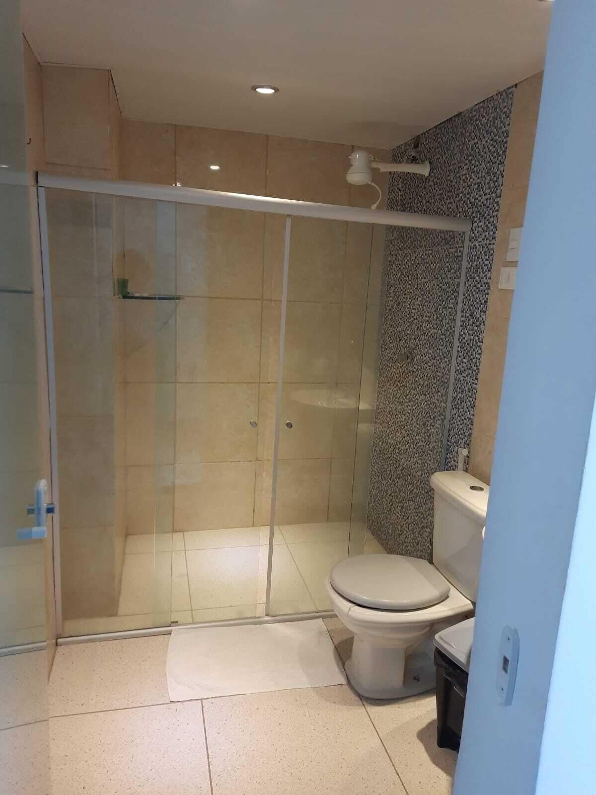 Un baño con ducha de vidrio, inodoro y lavamanos.