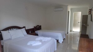 Habitación de hotel con dos camas, una mesita de noche de madera y una pequeña mesa.