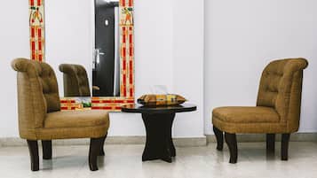 A room with two brown upholstered chairs, a small round table, and a mirror with a colorful border.