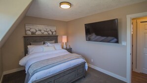 A bedroom with a bed, a nightstand, a wall-mounted TV, and a ceiling light.