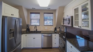 A modern kitchen with white cabinets, stainless steel appliances, and a granite countertop.