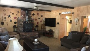 A cozy living room with a fireplace, comfortable seating, and a flat-screen TV. - Cabin in The Pines.. **Available 240v Tesla and EV charging.  (Heber-Overgaard)