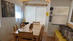 A dining area with a wooden table and chairs, a yellow sofa with patterned cushions, and a wall with decorative items. - Cabin in The Pines.. **Available 240v Tesla and EV charging.  (Heber-Overgaard)