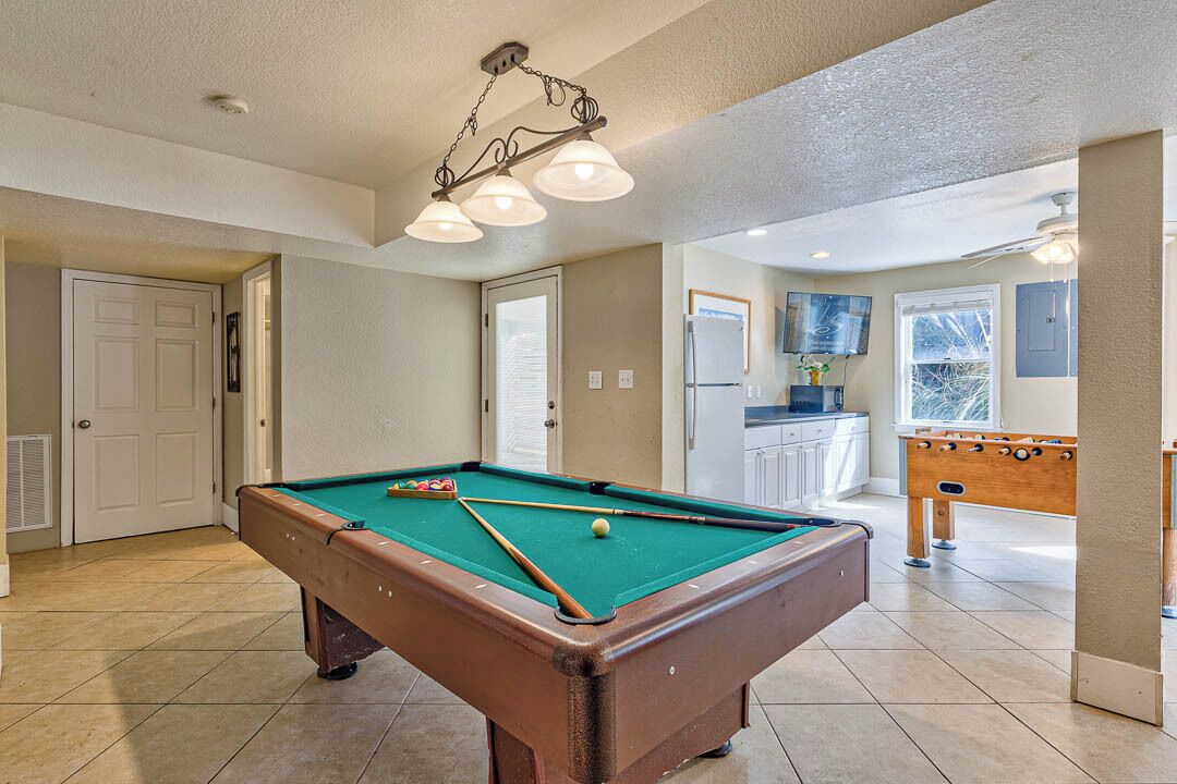 Een pooltafel in een ruimte met een kitchenette en een tafelvoetbal.
