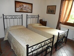 Una habitación con dos camas, un radiador y obras de arte en las paredes.