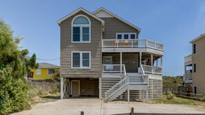 A two-story building with a balcony on the second floor, a covered front porch, and a garage. - Krosnest | Oceanfront | Private Pool, Hot Tub | Nags Head (Nags Head)
