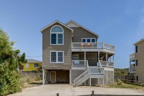 A two-story building with a balcony on the second floor, a covered front porch, and a garage. - Krosnest | Oceanfront | Private Pool, Hot Tub | Nags Head (Nags Head)