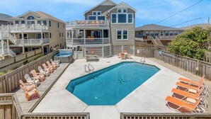 A residential building with a swimming pool, deck chairs, and a wooden fence. - Krosnest | Oceanfront | Private Pool, Hot Tub | Nags Head (Nags Head)