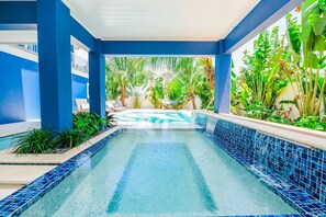 A swimming pool with blue mosaic tiles, surrounded by lush tropical plants and a hammock. - Palmetto Pointe! 5BR Luxury Home with Pool, Spa, Rooftop Deck and Walk to Beach (Anna Maria)