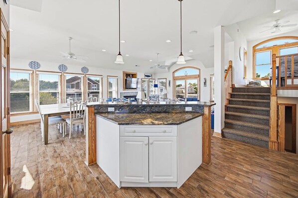 A spacious kitchen with a large island, wooden flooring, and a view of the outdoors.