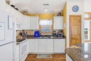 A kitchen with white cabinets, a microwave, a coffee maker, and a clock on the wall. - A Pirate's Paradise | 1499 ft from the beach | Dog Friendly, Private Pool, Hot Tub | Corolla (Corolla)