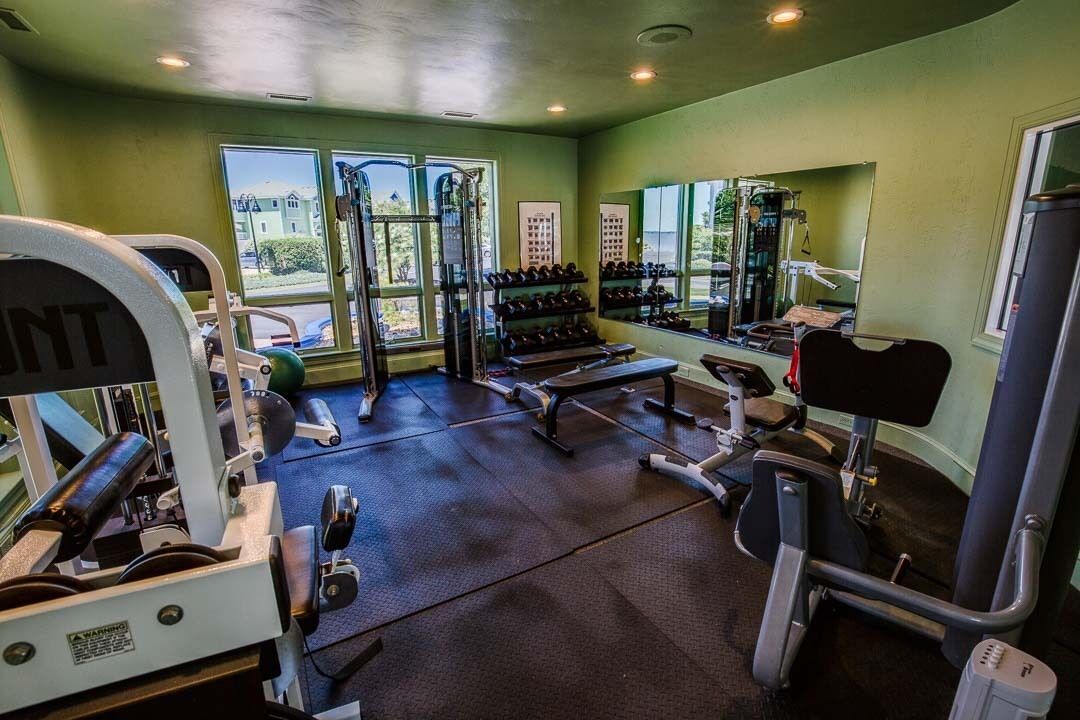 A gym with exercise equipment, a bench, and a mirror.