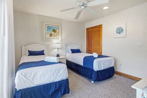 A hotel room with two beds, a ceiling fan, a painting, and a window with blinds. - A Pirate's Paradise | 1499 ft from the beach | Dog Friendly, Private Pool, Hot Tub | Corolla (Corolla)
