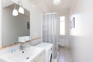 A bathroom with a white sink, a mirror, a shower curtain, and a toilet. - Rental In Rome Sistina View Terrace Apartment (Rome)