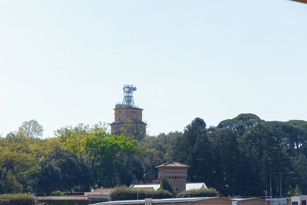 A tower with a metal framework, surrounded by trees and buildings with traditional architecture. - Rental In Rome Sistina View Terrace Apartment (Rome)