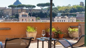 A terrace with outdoor furniture, potted plants, and a view of a historic building with a dome. - Rental In Rome Sistina View Terrace Apartment (Rome)