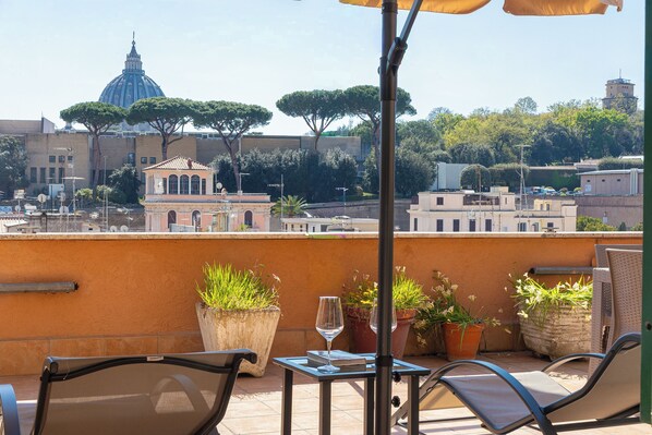 A terrace with outdoor furniture, potted plants, and a view of a historic building with a dome. - Rental In Rome Sistina View Terrace Apartment (Rome)