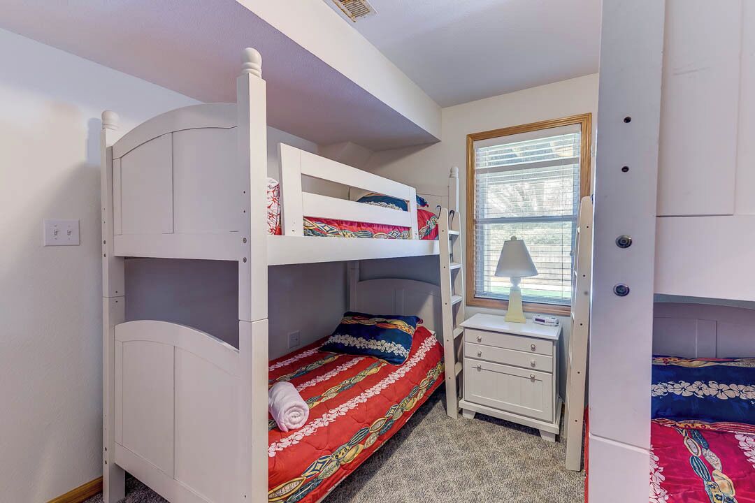 A bunk bed room with a desk and a window.